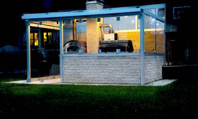überdachte Outdoorküche aus Glas, Aluminium und Stein mit Falttüren
